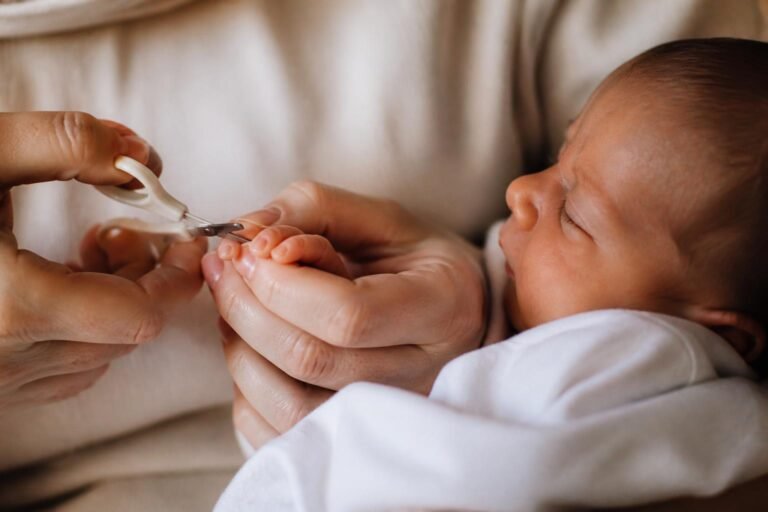 Parent gently trimming a newborn's fingernails with baby scissors