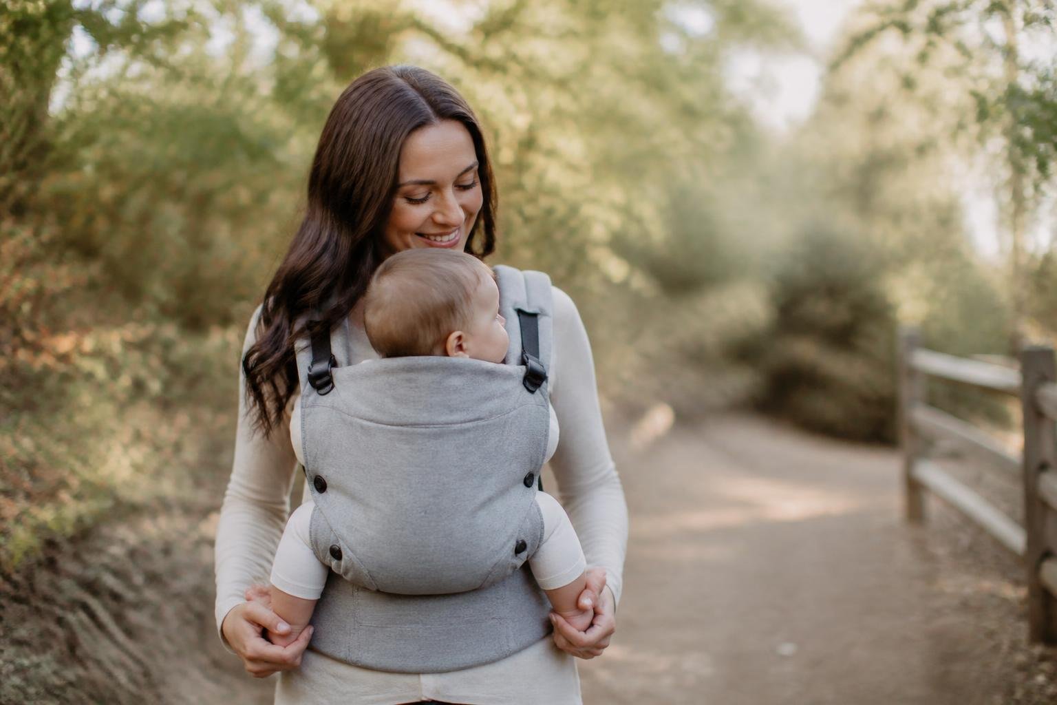 Parent carrying baby in an ergonomic carrier in healthy M-position